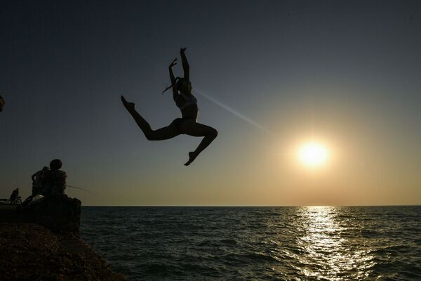 فتاة تقفز إلى مياه البحر الأسود في بلدة نوفوفيودوروفكا في منطقة ساكي، القرم - سبوتنيك عربي
