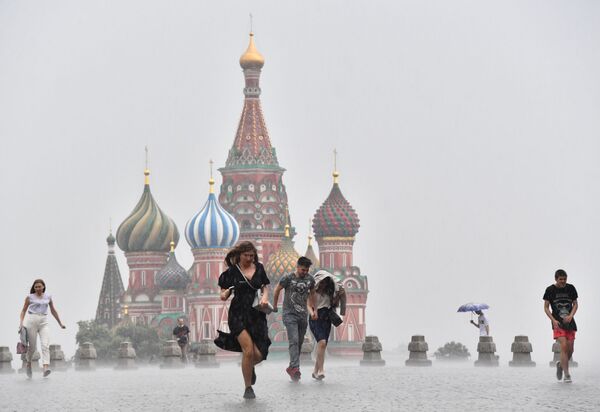 أشخاص يركضون في الساحة الحمراء أثناء هطول أمطار غزيرة في موسكو، 7 يوليو 2020 - سبوتنيك عربي