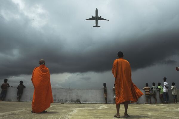 الرهبان البوذيون والأطفال يشاهدون طائرة تقلع من مطار نيتاجي سوبهاس تشاندرا بوس الدولي في كلكتا، بعد رفع قيود الحجر الصحي في الهند 5 يوليو 2020 - سبوتنيك عربي