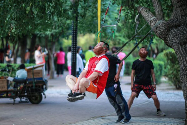 تظهر هذه الصورة التي التقطت في 5 يوليو 2020 رجلاً يقوم بتمرين للرقبة، وهو معلق على غضن شجرة في شنيانغ، بمقاطعة لياونينغ شمال شرق الصين - سبوتنيك عربي