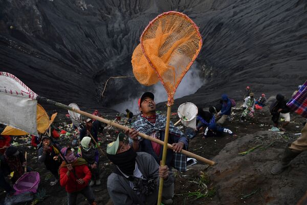 قرويون محليون يمسكون بشبكات ويلتقطون القطع النقدية التي يلقيها الحجاج الهندوس في فوهة بركان برومو أثناء احتفال كاسادا الهندوسي، إندونيسيا 7 يوليو 2020 - سبوتنيك عربي