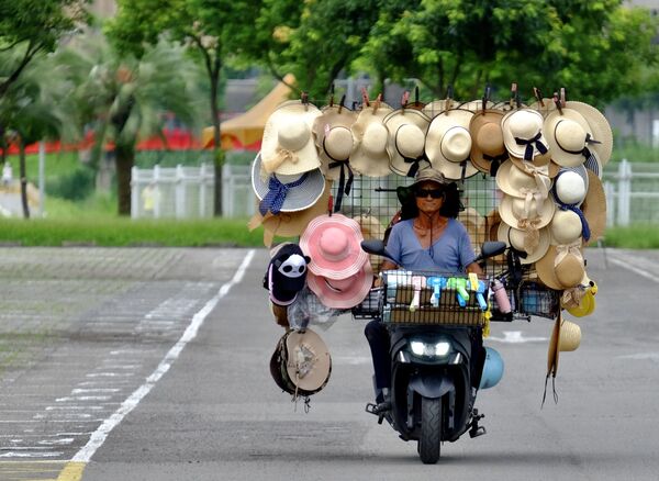 وانغ شانغ-تشي، 75 عاما، بائع قبعات متجول، يقود دراجته في موقف للسيارات بجوار حديقة حيوانات مدينة تايبيه في تايوان، 9 يوليو 2020. - سبوتنيك عربي