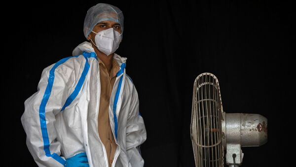 موظف من القطاع الصحي يأخذ استراحة أثناء انتظار الناس لجمع عينات لإجراء اختبارات لمرض الفيروس التاجي (كوفيد-19)، وسط انتشار الوباء في نيودلهي، الهند  10 يوليو 2020. - سبوتنيك عربي
