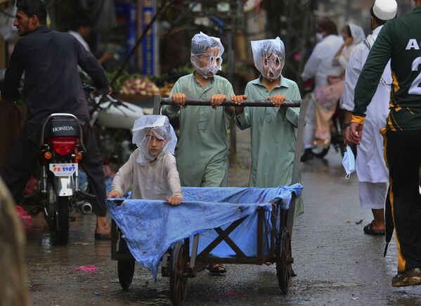 صبيان يغطون وجوههم بأكياس بلاستيكية أثناء دفع عربة يد أثناء هطول الأمطار في بيشاور، باكستان 12 يوليو 2020 - سبوتنيك عربي