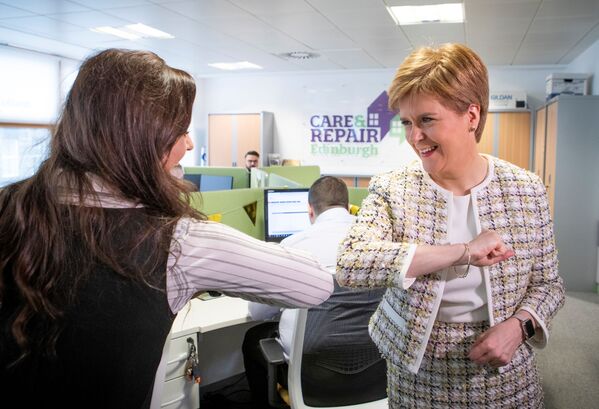 الوزيرة الأولى لاسكتلندا نيكولا ستارجن  (يمين) تلقي التحية بكوعها خلال زيارتها لمكتب الاتصالات الطارئة (خط المساعدة للمسنين في اسكتلندا المدعوم من الحكومة الاسكتلندية) في إطار مكافحة وباء كورونا، في أدنبره في 18 مارس 2020 - سبوتنيك عربي