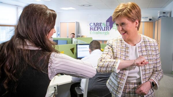الوزيرة الأولى لاسكتلندا نيكولا ستارجن  (يمين) تلقي التحية بكوعها خلال زيارتها لمكتب الاتصالات الطارئة (خط المساعدة للمسنين في اسكتلندا المدعوم من الحكومة الاسكتلندية) في إطار مكافحة وباء كورونا، في أدنبره في 18 مارس 2020 - سبوتنيك عربي