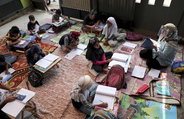 المعلمة والتلاميذ يرتدون كمامات طبية أثناء الدرس في تانغيرانغ، في إطار الاجراءات الاحترازية لمنع تفشي فيروس كورونا، إندونيسيا 10 أغسطس 2020 - سبوتنيك عربي
