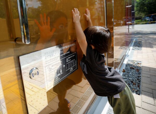 طفل ينظر إلى أمه عبر الجدران الشفافة لمرحاض عام في حديقة يويوجي فوكاماتشي ميني بارك في طوكيو، اليابان 26 أغسطس 2020 - سبوتنيك عربي