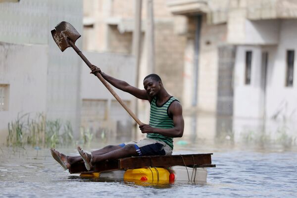 أحد أهالي مدينة كور-مساري يركب طوفا مؤقتا في الشوارع التي غمرتها المياه بعد هطول أمطار غزيرة، السنغال 9 سبتمبر 2020 - سبوتنيك عربي