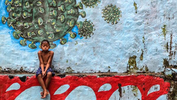 طفل يجلس أمام لوحة جدارية تمثل فيروس كورونا المسبب لمرض كوفيد -19 في بوكور، جاوة الغربية بإندونيسيا، 27 سبتمبر 2020 - سبوتنيك عربي