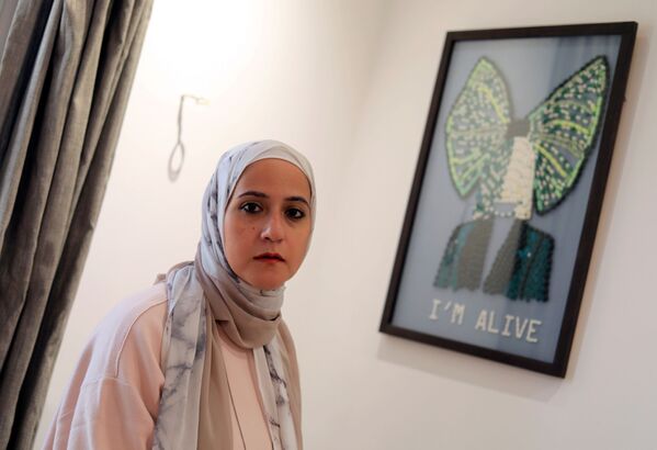 الفنانة المصرية أمل صلاح (35 عاما)، تقف على خلفية لوحة بعنوان I'm Alive (أنا حي) في منزلها، القاهرة 6 أكتوبر 2020 - سبوتنيك عربي