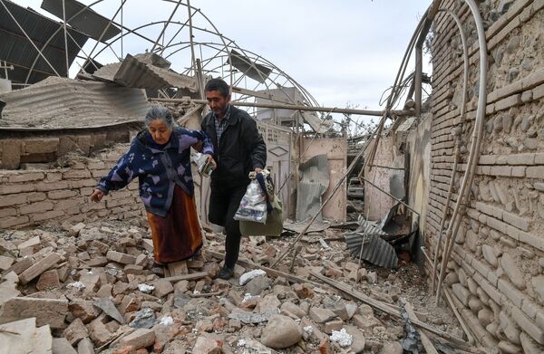 سكان منزل دمره قصف على مدينة كنجه في أذربيجان، في ظل التصعيد العسكري بين أرمينيا وأذربيجان، 4 أكتوبر 2020 - سبوتنيك عربي