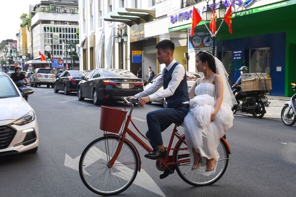 عريس ينقل عروسه على دراجة هوائية وهم يقفون لالتقاط صور زفاف في أحد شوارع هانوي، فيتنام 2 أكتوبر 2020 - سبوتنيك عربي
