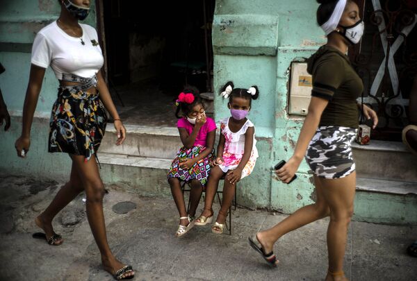 طفلتان ترتديان كمامات كإجراء احترازي ضد انتشار فيروس كورونا، تنتظران والديهما لأخذهما خارج المنزل في هافانا، كوبا، 12 أكتوبر 2020 - سبوتنيك عربي