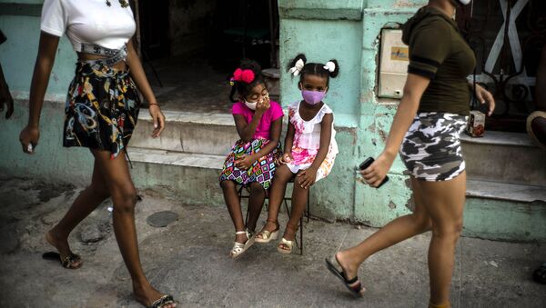 طفلتان ترتديان كمامات كإجراء احترازي ضد انتشار فيروس كورونا، تنتظران والديهما لأخذهما خارج المنزل في هافانا، كوبا، 12 أكتوبر 2020 - سبوتنيك عربي