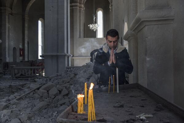 أحد السكان المحليين يصلي في كنيسة دمرها القصف في مدينة شوشي، في منطقة النزاع بين أرمينيا وأذربيجان بقره باغ، 11 أكتوبر 2020. - سبوتنيك عربي