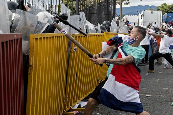 متظاهر يضع علم كوستاريكا يحمل أنبوبا معدنيا، يواجه شرطة مكافحة الشغب خلال احتجاجات على مقترح الحكومة بزيادة الضرائب في غطار التوصل إلى اتفاقية ائتمان مع صندوق النقد الدولي (IMF) ، خارج المقر الرئاسي في سان خوسيه، كوستاريكا في 12 أكتوبر 2020 - سبوتنيك عربي