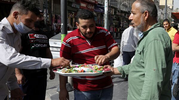 مواطن أردني يقوم بتوزيع الحلو على الزبائن والمارة بمناسبة إحياء ذكرى المولد النبوي في مدينة عمان، الأردن  29 أكتوبر/ تشرين الأول 2020 - سبوتنيك عربي