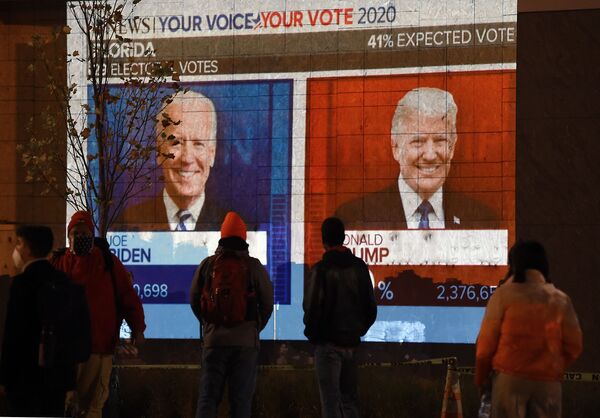 مواطنون يراقبون نتائج التصويت في الانتخابات الرئاسية الأمريكية 2020 على شاشة تلفاز كبيرة في أحد شوارع مدينة واشنطن، 3 نوفمبر 2020 - سبوتنيك عربي