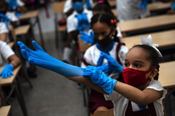 تلميذة ترتدي كمامة وقفازات كإجراء احترازي وسط انتشار فيروس كورونا خلال الفصل الدراسي في هافانا، كوبا، 2 نوفمبر 2020 - سبوتنيك عربي