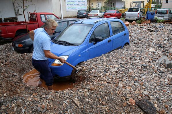 رجل يخرج سيارته العالقة إثر هطول أمطار غزيرة في ماليا بجزيرة كريت، اليونان 10 نوفمبر 2020 - سبوتنيك عربي