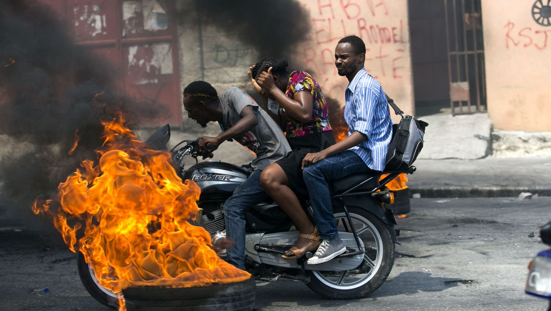 دراجة نارية أجرة تمر بجانب إطار محترق في بورت أو برنس، هاييتي - سبوتنيك عربي, 1920, 11.07.2021