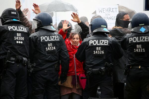 متظاهرون يرفعون أيديهم أمام ضباط الشرطة خلال احتجاجات ضد قيود الحكومة الألمانية التي فرضتها لاحتواء وباءكورونا (كوفيد-19) ، بالقرب من بوابة براندنبورغ في برلين، 18 نوفمبر 2020. - سبوتنيك عربي