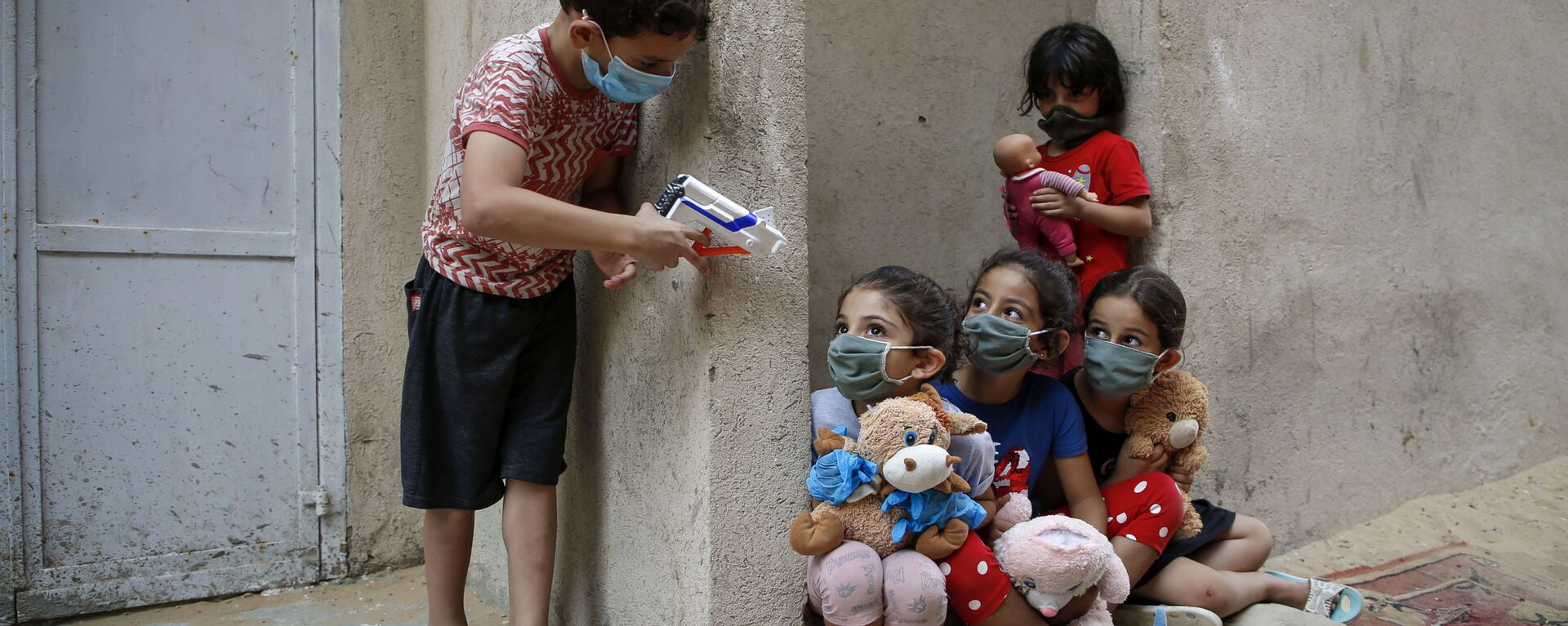 أطفال فلسطينيون يرتدون كمامات بسبب وباء فيروس كورونا كوفيد-19، يلعبون خارج منزلهم في مدينة غزة، 8 سبتمبر  2020. - سبوتنيك عربي, 1920, 12.12.2020