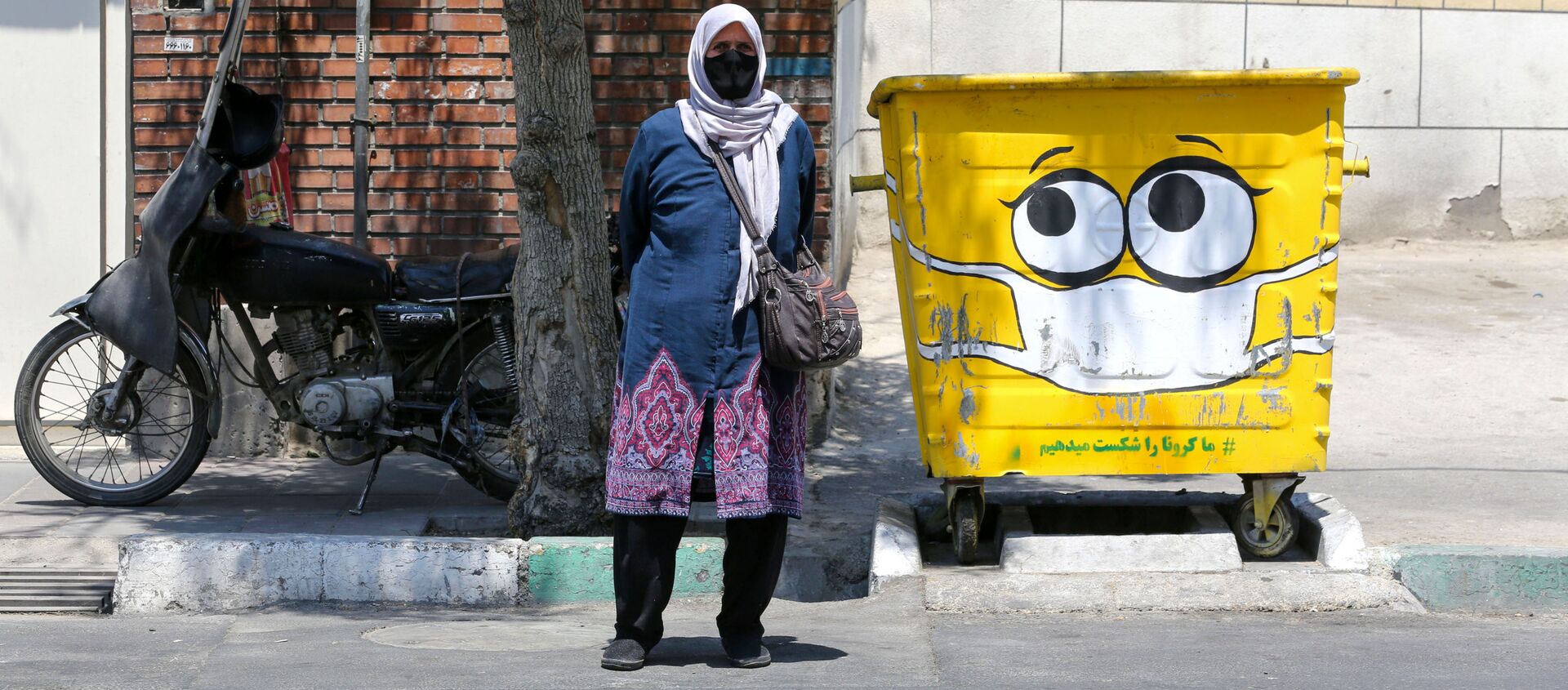 امرأة تقف بجوار سلة القمامة المرسوم عليها كمامة، في إطار حملة لنشر الوعي حول جائحة كورونا، في حي جنوبي بالعاصمة الإيرانية طهران في 18 يوليو 2020. - سبوتنيك عربي, 1920, 28.04.2021