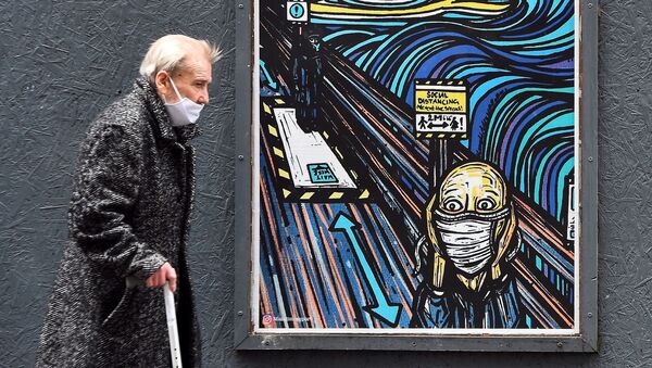 مسن يرتدي كمامة يسير من أمام رسم غرافيتي على جدار مستوحاة من العمل الفني الشهير الصرخة للفنان النرويجي إدوارد مونك، ولكن الشخصية أيضا ترتدي كمامة، في غلاسكو،  2 سبتمبر 2020  - سبوتنيك عربي