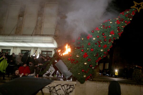 متظاهرون يحرقون شجرة عيد الميلاد أمام مبنى رئيس الوزراء الألباني خلال اشتباكات مع شرطة الأمن ومكافحة الشغب في مدينة تيرانا، ألبانيا 9 ديسمبر 2020. - سبوتنيك عربي
