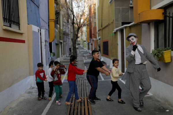 محمد، فنان شوارع إيراني يرتدي زي شخصية الجوكر، يقف مع أعضاء فرقة مسرحية أثناء عرض ترفيهي للمواطنين، وسط تفشي كورونا (كوفيد-19) في طهران، إيران، 12 ديسمبر 2020 - سبوتنيك عربي