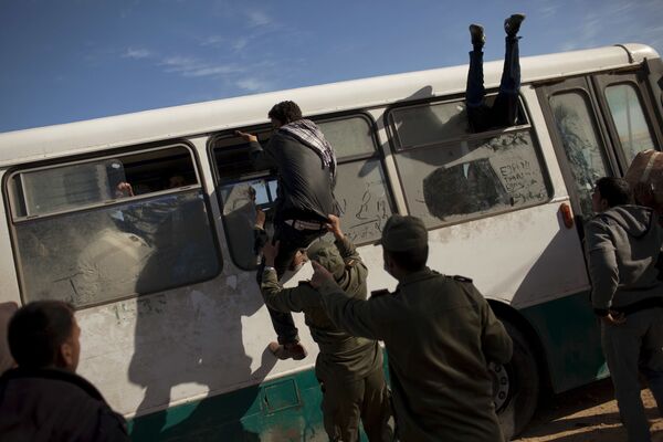 مصريون يحاولون ركوب حافلة بينما يحاول جندي من الجيش التونسي إيقاف أحدهم  في رأس جدير، على الحدود التونسية الليبية، تونس، 3 مارس 2011 - سبوتنيك عربي