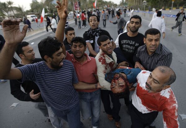 نقل أحد المصابين خلال مظاهرة مناهضة للحكومة البحرينية إلى سيارة ليتم نقله إلى المستشفى في المنامة، البحرين، 18 فبراير 2011 - سبوتنيك عربي