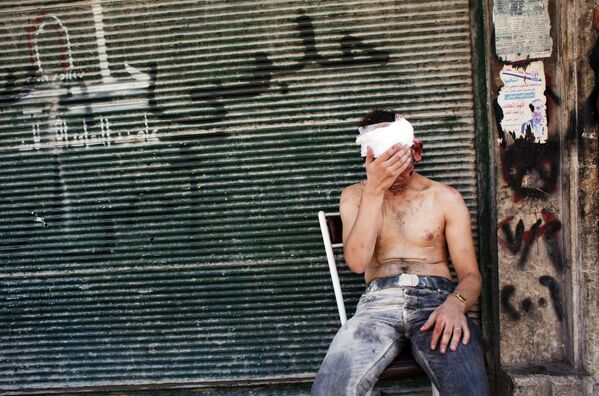 في هذه الصورة التي التقطت في 4 سبتمبر 2012، يجلس رجل سوري أصيب جراء القصف على كرسي خارج متجر مغلق في منطقة المواصلات في حلب. - سبوتنيك عربي