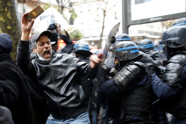 قوات الشرطة لمكافحة الشغب يقبضون على رجل كان يمسك هاتفه خلال الاحتجاجات، في باريس 12 ديسمبر 2020 - سبوتنيك عربي