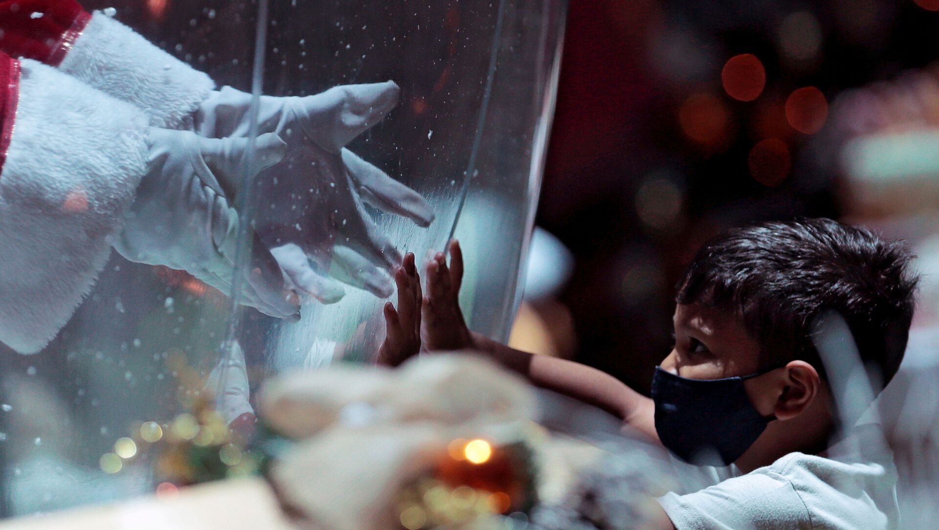 أبيليو دا كروز بينتو، 77 عامًا، يرتدي زي بابا نويل داخل فقاعة بلاستيكية، يحيي طفلًا في مركز تسوق وسط تفشي فيروس كورونا (كوفيد-19) في برازيليا، البرازيل، 15 ديسمبر 2020. - سبوتنيك عربي, 1920, 23.03.2021