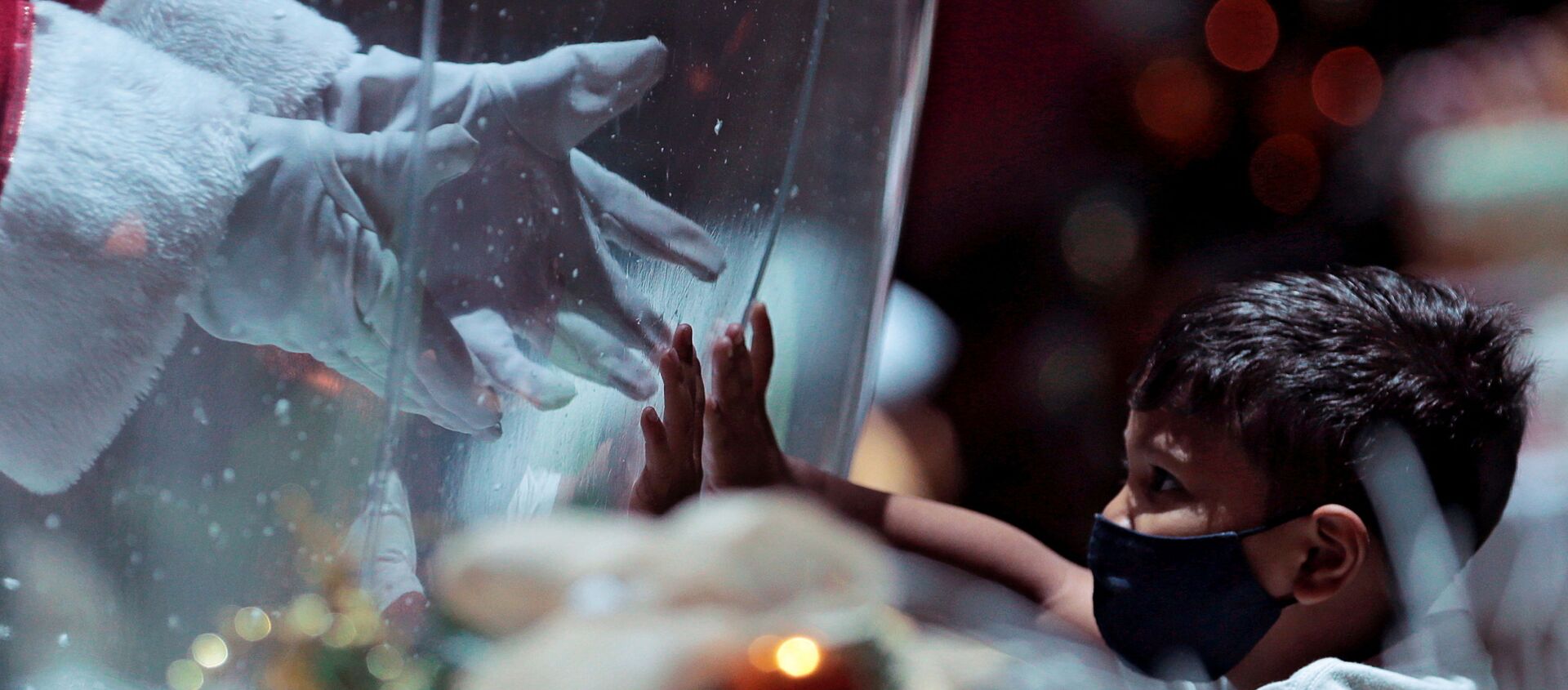 أبيليو دا كروز بينتو، 77 عامًا، يرتدي زي بابا نويل داخل فقاعة بلاستيكية، يحيي طفلًا في مركز تسوق وسط تفشي فيروس كورونا (كوفيد-19) في برازيليا، البرازيل، 15 ديسمبر 2020. - سبوتنيك عربي, 1920, 23.03.2021
