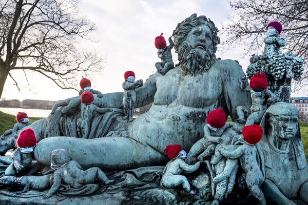 تماثيل برونزية صغيرة عند تمثال نيلين (النيل) في كوبنهاغن مغطاة بقبعات حمراء وكمامات صغيرة وسط أجواء الاستعداد بالاحتفال بالعيد الميلاد ورأس السنة وتفشي كورونا، الدنمارك 16 ديسمبر 2020 - سبوتنيك عربي