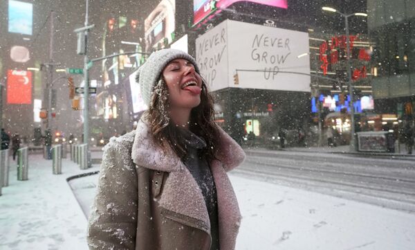 فتاة تقف وسط ميدان تايم سكوير في مدينة نيويورك، تلتقط حبات ثلج، إثر تساقط ثلوج كثيفة في المدينة، ديسمبر 17 ديسمبر 2020 - سبوتنيك عربي