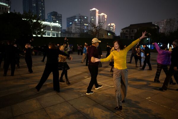 الناس يرقصون في حديقة عامة في الليل، بعد عام تقريبًا من تفشي مرض فيروس كورونا المستجد (كوفيد-19) في ووهان، مقاطعة هوبي، الصين، 11 ديسمبر 2020 - سبوتنيك عربي