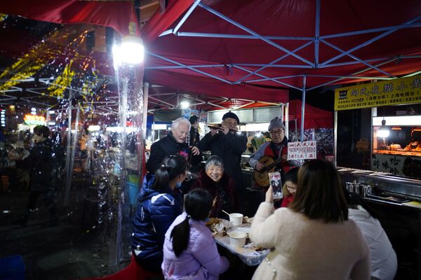 الناس يأكلون في مطعم في أحد شوارع المدينة ليلاً، بعد عام تقريبًا من تفشي مرض فيروس كورونا (كوفيد-19) في ووهان، مقاطعة هوبي، الصين 11 ديسمبر 2020 - سبوتنيك عربي