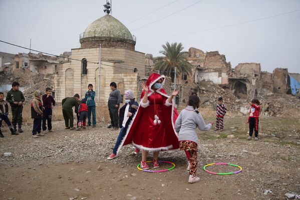 امرأة عراقية ترتدي زي بابا نويل وهي تلعب مع أطفال مدينة الموصل القديمة، العراق 18 ديسمبر 2020 - سبوتنيك عربي