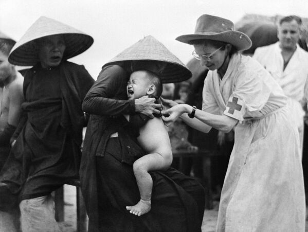 ماري جوزيت فرانكو (يمين) ، ممرضة استعمارية، أثناء تلقيح طفل ضد الكوليرا في مونغ دوك، الهند الصينية،  10 أكتوبر 1953 - سبوتنيك عربي
