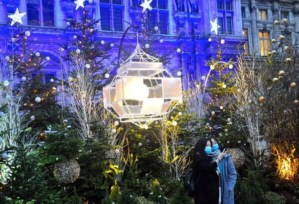 سياح يلتقطون صور سيلفي على خلفية أشجار غيد الميلاد بالقرب من قاعة مدينة فندق أوتيل دي فيل في باريس، فرنسا  21ديسمبر 2020 - سبوتنيك عربي