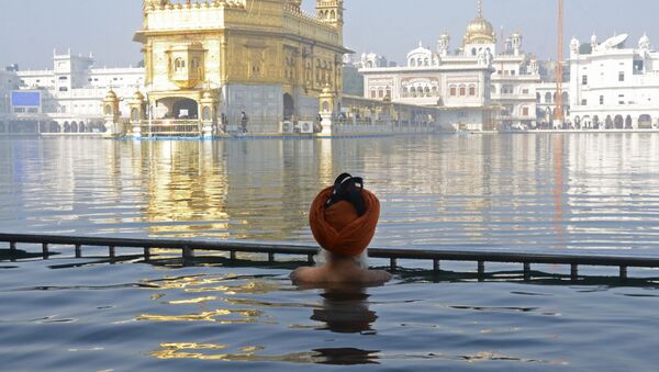 أحد المخلصين السيخيين يغطس في مياه ساروفار المقدسة التابعة للمعبد الذهبي في يوم استشهاد السيخ غورو تيغه بهادور التاسع، في أمريتسار، الهند 19 ديسمبر 2020 - سبوتنيك عربي