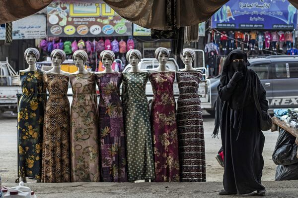 امرأة تمر أمام أزياء معروضة في مدينة الرقة شمال سوريا، 20 ديسمبر 2020 - سبوتنيك عربي