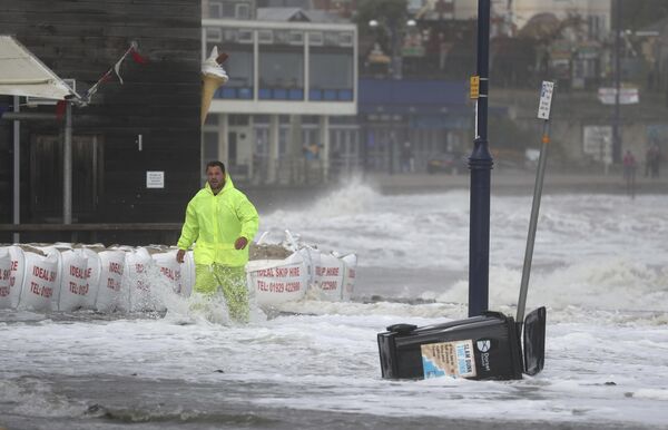رجل يسير عبر المياه التي غمرت شوارع المدينة الساحلية في سواناج في دورست، جراء  لعاصفة أليكس التي ضربت إنجلترا، 2 أكتوبر 2020. - سبوتنيك عربي