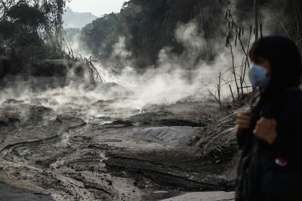 قروي يشاهد مجرىًا بخاريًا ناجمًا عن تدفق الحمم البركانية، عقب ثوران بركان جبل سيميرو، في منطقة وصاية لوماجانغ، تقع في جاوة الشرقية بإندونيسيا، 2 ديسمبر 2020 - سبوتنيك عربي
