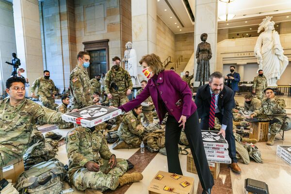 عضوا مجلس النواب الأمريكي فيكي هارتزلر ومايكل والتز يقومان بتوزيع البيتزا على عناصر قوات الحرس الوطني الأمريكي في مبنى الكابيتول، واشنطن 13 يناير 2021 - سبوتنيك عربي
